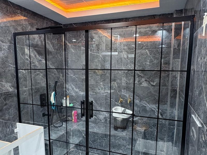 Köşe tip duşakabin — siyah mat profil, üst şeffaf alt buzlu cam, lüks banyo