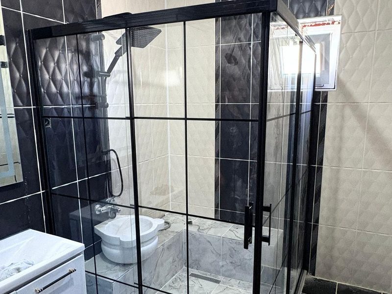 Köşe tip duşakabin — siyah mat profil, üst şeffaf alt buzlu cam, desenli fayans banyo